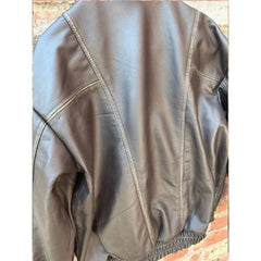Back view of a brown leather jacket with visible panel stitching and gathered waistband.