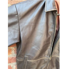 Close-up of brown leather jacket with zipper and pocket against brick wall