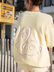 Back view of Lo Crew pale yellow sweatshirt with lilac embroidered outline design