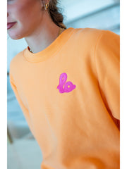 Lo Crew Coral orange crewneck sweatshirt with pink puff embroidered logo, studio shot
