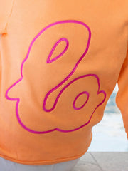 Lo Crew Coral orange sweatshirt back detail with pink outline logo, poolside backdrop