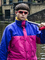 Oliver Tree blue pink colorblock track jacket close up outdoor canal scene