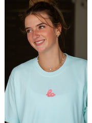 Mint green oversized t-shirt with small chest logo detail, indoor setting